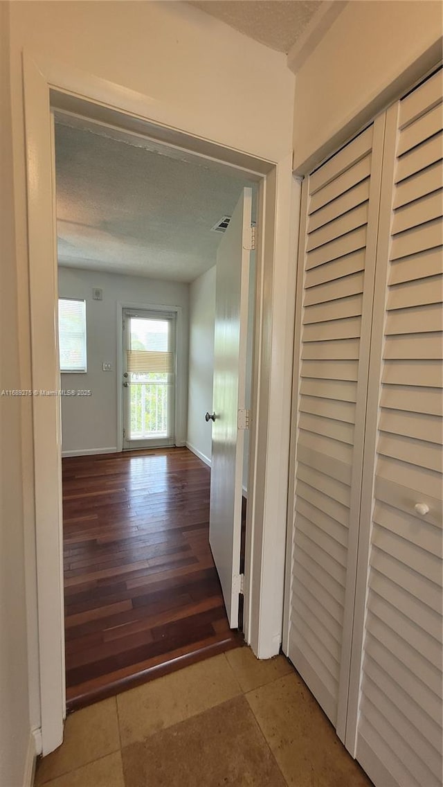 corridor featuring tile patterned floors and a textured ceiling