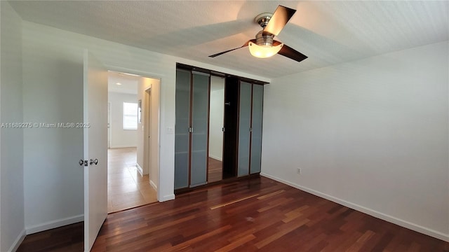 unfurnished bedroom with a textured ceiling, ceiling fan, and dark wood-type flooring