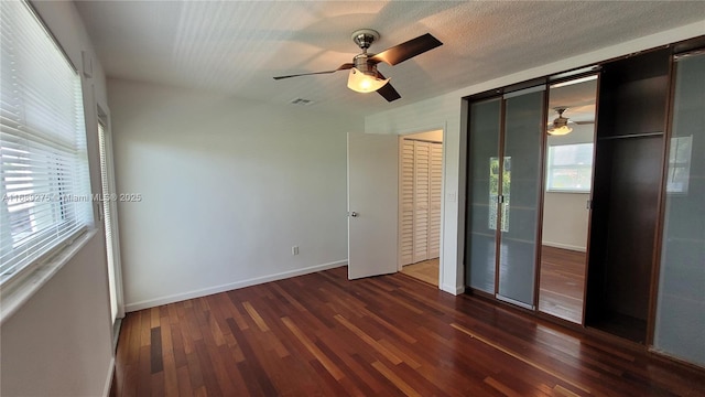 unfurnished bedroom with ceiling fan and dark wood-type flooring