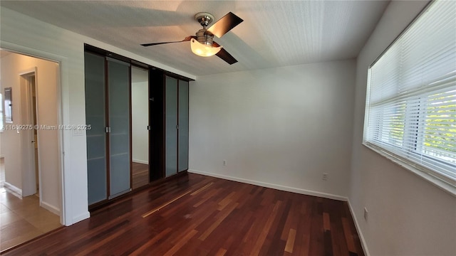 unfurnished bedroom with a barn door, dark hardwood / wood-style floors, and ceiling fan