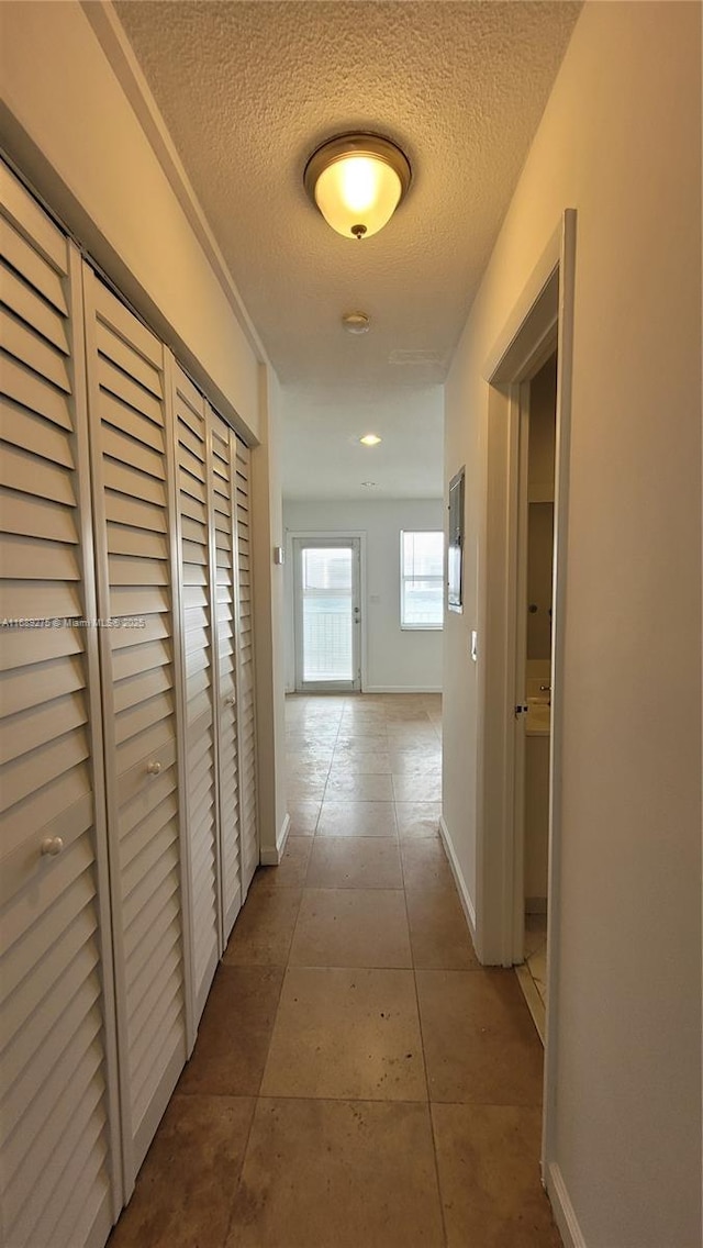 hall featuring tile patterned flooring and a textured ceiling