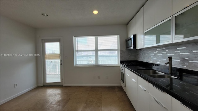 kitchen featuring tasteful backsplash, sink, white cabinets, and stainless steel appliances