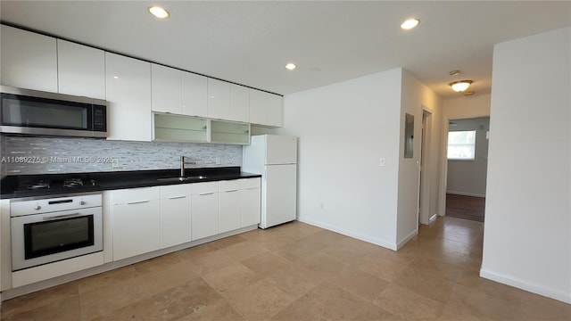 kitchen with tasteful backsplash, white appliances, sink, electric panel, and white cabinetry