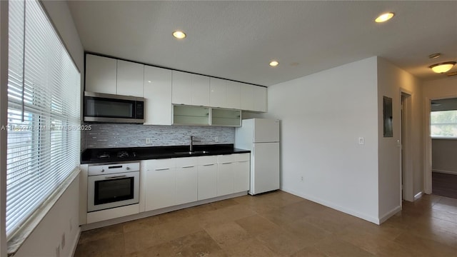 kitchen featuring white cabinets, sink, white appliances, and backsplash