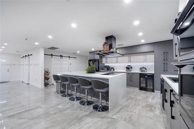 kitchen with a kitchen bar, a kitchen island, a barn door, gray cabinets, and wine cooler