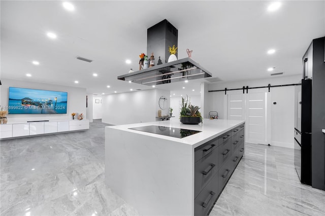 kitchen with gray cabinetry, a center island, black appliances, a barn door, and island exhaust hood