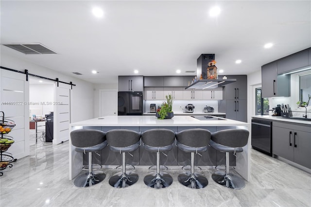 kitchen featuring a large island, a kitchen breakfast bar, a barn door, and island exhaust hood