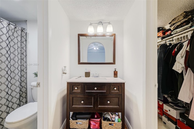 bathroom featuring a shower with curtain, vanity, toilet, and a textured ceiling