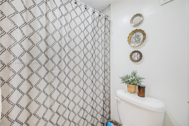 bathroom featuring toilet and curtained shower