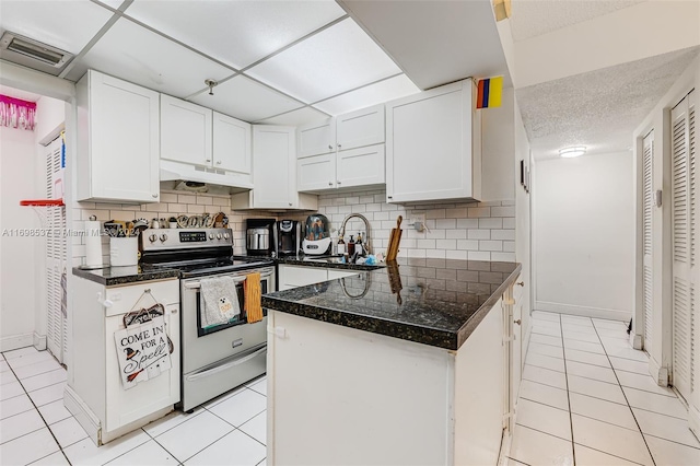 kitchen featuring backsplash, electric stove, and white cabinetry