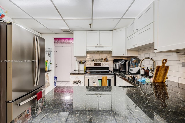 kitchen with a drop ceiling, white cabinets, sink, dark stone countertops, and stainless steel appliances