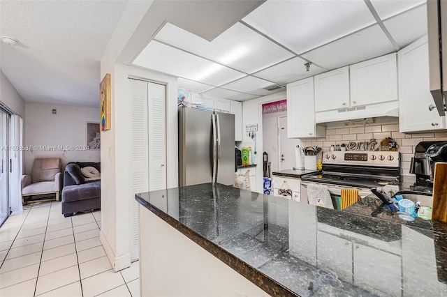 kitchen with appliances with stainless steel finishes, backsplash, dark stone counters, light tile patterned floors, and white cabinets