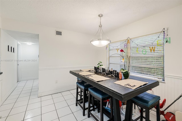 dining space with light tile patterned floors and a textured ceiling