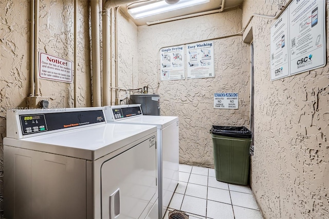 washroom featuring water heater, light tile patterned flooring, and washer and dryer