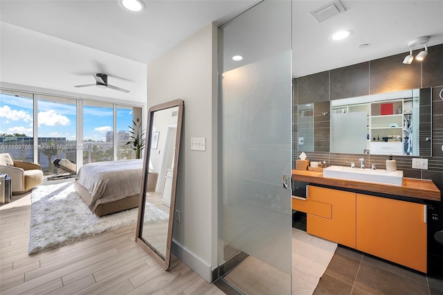 bathroom featuring backsplash, vanity, a shower with door, ceiling fan, and wood-type flooring