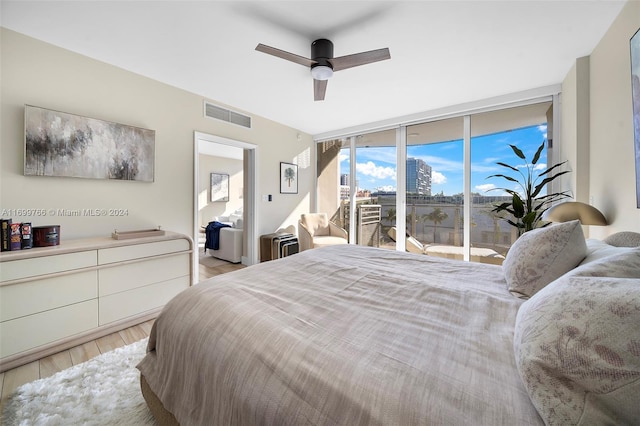 bedroom featuring ceiling fan, light hardwood / wood-style floors, access to exterior, and a wall of windows