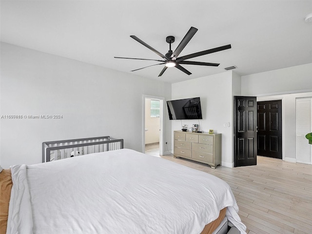 bedroom featuring ensuite bath, light hardwood / wood-style flooring, and ceiling fan