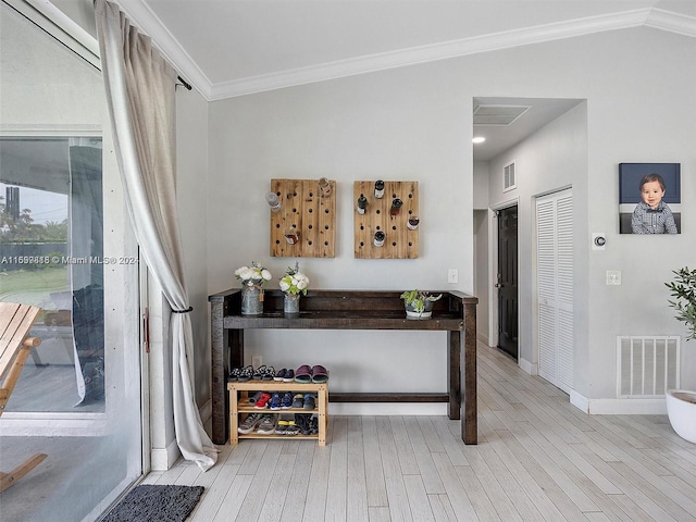 interior space featuring light hardwood / wood-style floors, vaulted ceiling, and ornamental molding