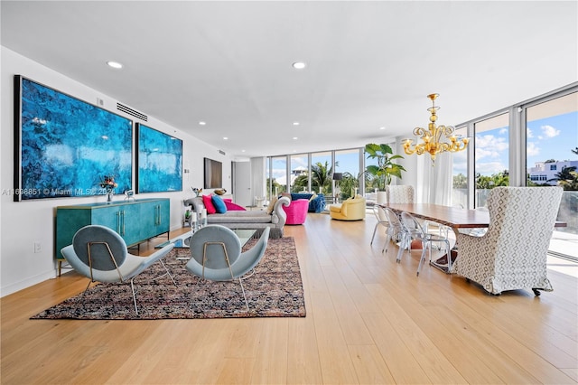 living room featuring a healthy amount of sunlight, a wall of windows, light hardwood / wood-style floors, and a chandelier