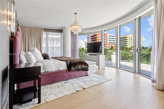 bedroom with access to outside, light hardwood / wood-style floors, floor to ceiling windows, and a notable chandelier