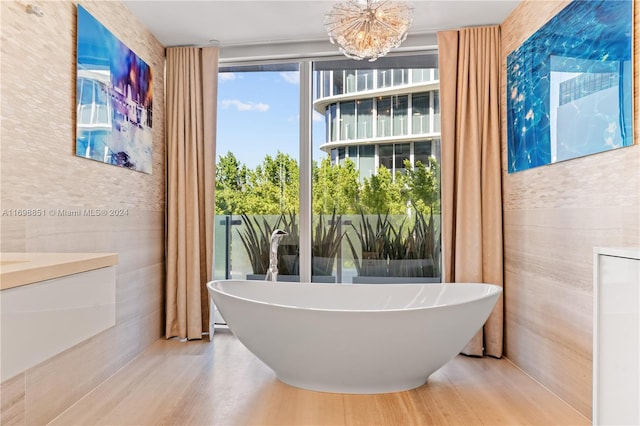 bathroom with hardwood / wood-style flooring, an inviting chandelier, and a bathtub