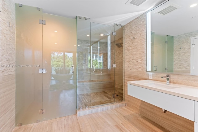 bathroom featuring vanity, a shower with shower door, tile walls, and wood-type flooring