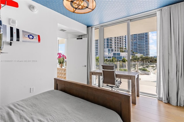 bedroom featuring floor to ceiling windows, hardwood / wood-style flooring, and multiple windows