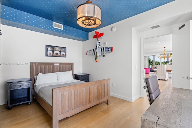 bedroom featuring a chandelier and light wood-type flooring