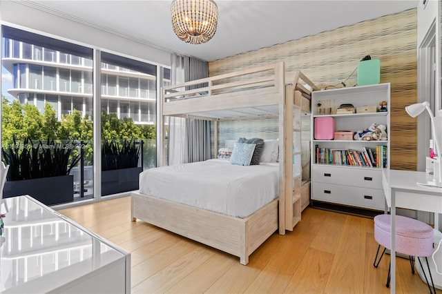 bedroom featuring access to outside, light hardwood / wood-style floors, and an inviting chandelier