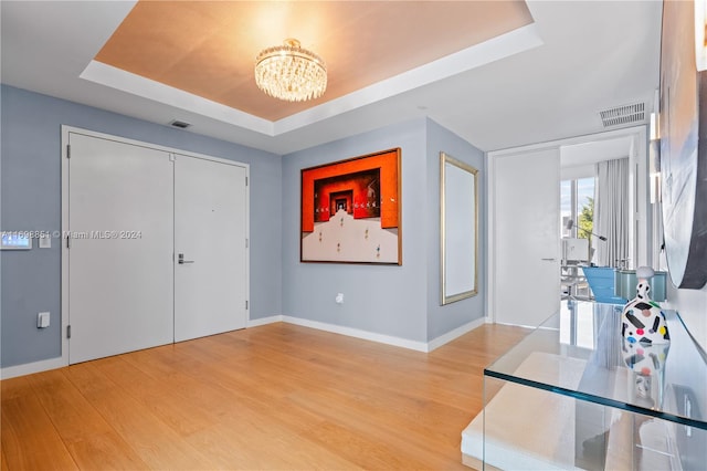 foyer with a chandelier, hardwood / wood-style flooring, and a raised ceiling