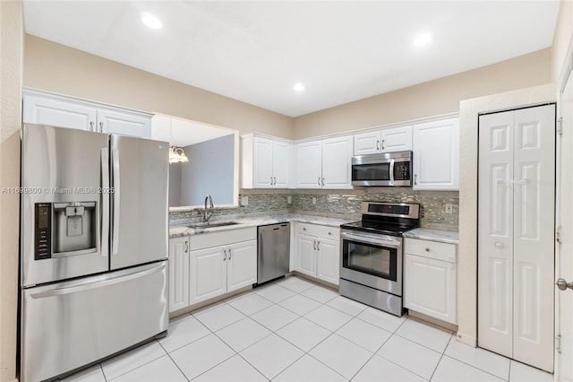 kitchen with stainless steel appliances, decorative backsplash, white cabinets, and sink