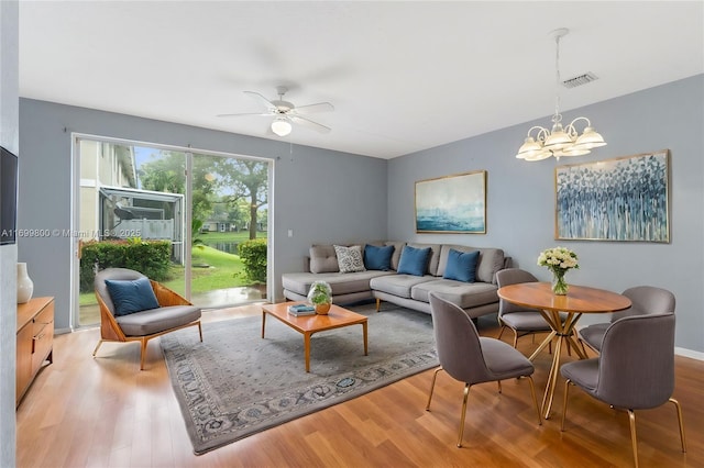 living room with ceiling fan with notable chandelier and light hardwood / wood-style flooring