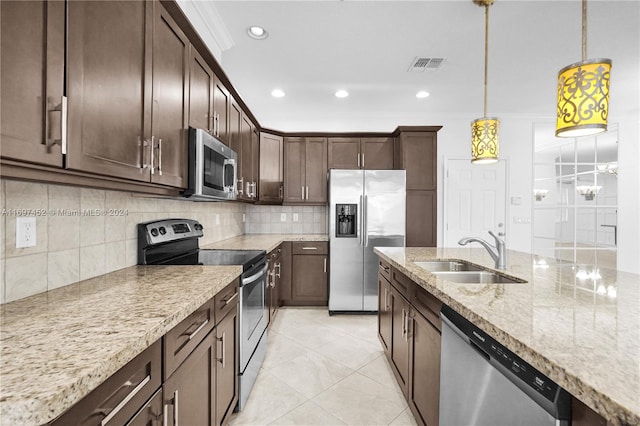 kitchen featuring sink, hanging light fixtures, light stone counters, dark brown cabinets, and appliances with stainless steel finishes