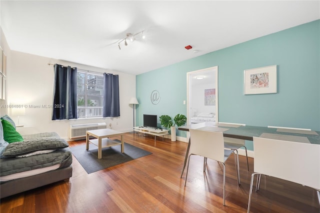 living room featuring wood-type flooring, rail lighting, and a wall unit AC