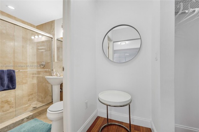 bathroom with hardwood / wood-style flooring, an enclosed shower, and toilet