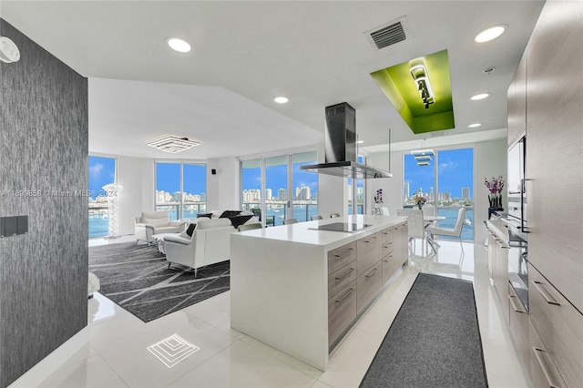 kitchen featuring a center island, a wall of windows, light tile patterned floors, and exhaust hood