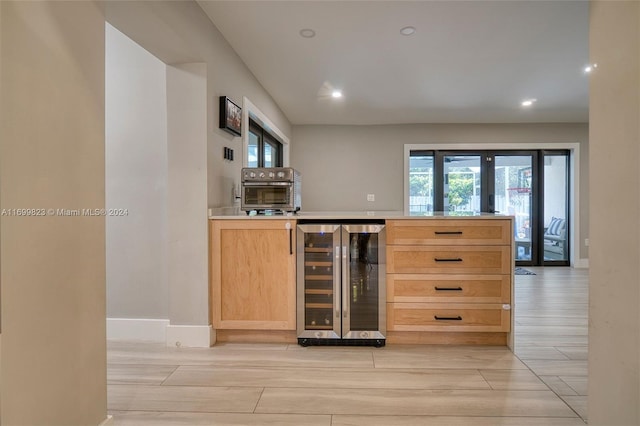 bar featuring light brown cabinetry, light hardwood / wood-style floors, wine cooler, and a healthy amount of sunlight