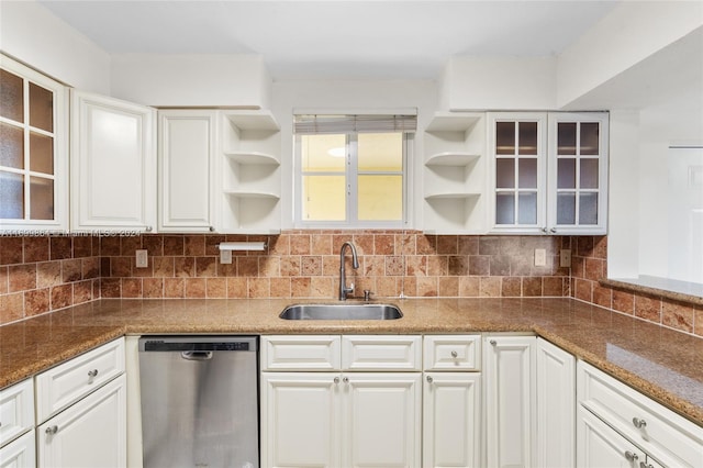 kitchen featuring white cabinets, sink, stainless steel dishwasher, dark stone countertops, and tasteful backsplash