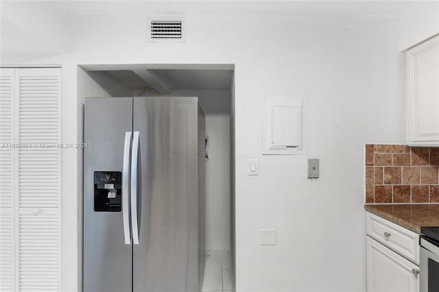 kitchen featuring tasteful backsplash, white cabinetry, dark stone counters, and stainless steel refrigerator with ice dispenser