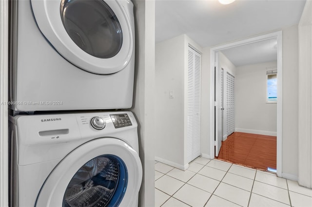 laundry area with light tile patterned flooring and stacked washer and dryer