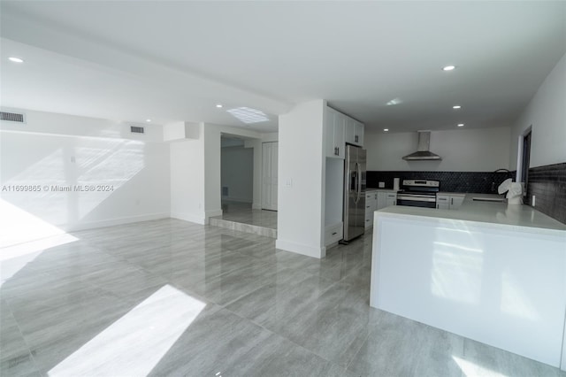 kitchen featuring white cabinets, sink, wall chimney exhaust hood, kitchen peninsula, and stainless steel appliances