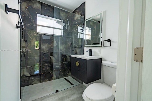 bathroom featuring vanity, a shower with shower door, and toilet