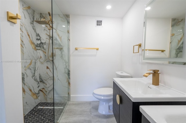 bathroom with a tile shower, tile patterned flooring, vanity, and toilet