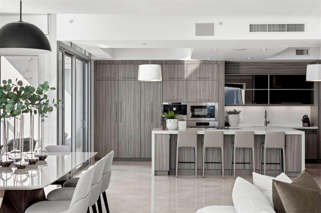 kitchen featuring stainless steel microwave, plenty of natural light, a kitchen breakfast bar, and sink