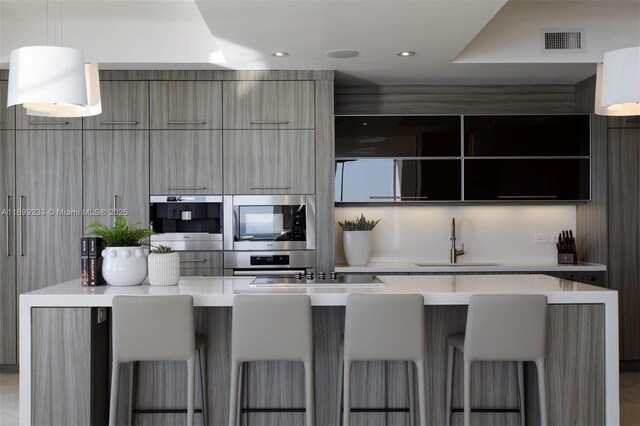 kitchen featuring stainless steel appliances, sink, a breakfast bar area, and decorative light fixtures