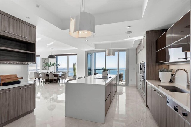 kitchen with sink, a water view, a center island, appliances with stainless steel finishes, and pendant lighting