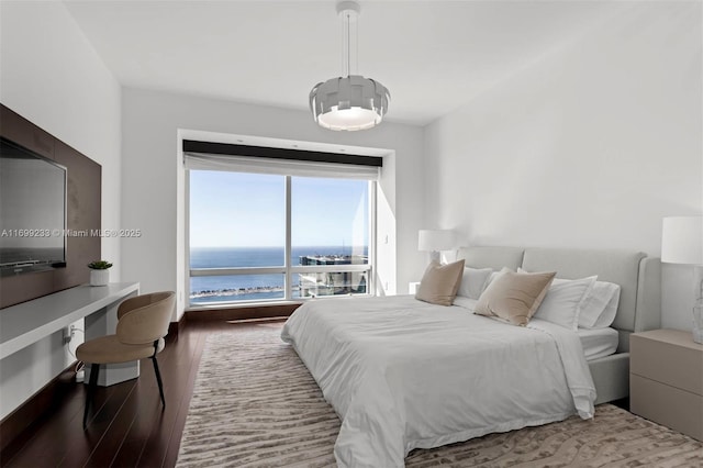 bedroom featuring wood-type flooring and a water view