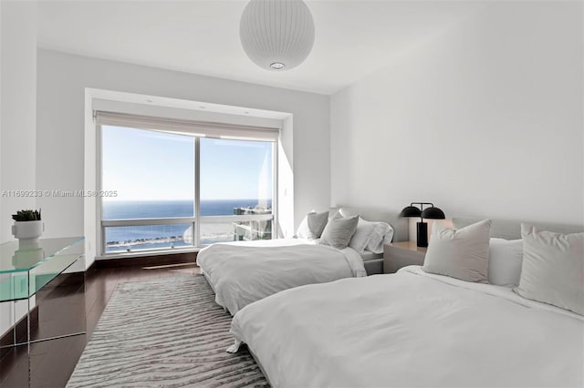 bedroom with dark hardwood / wood-style floors and a water view