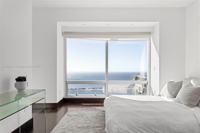 bedroom with dark wood-type flooring and a water view