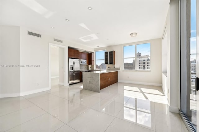 kitchen featuring stainless steel appliances, a kitchen island, and light tile patterned flooring